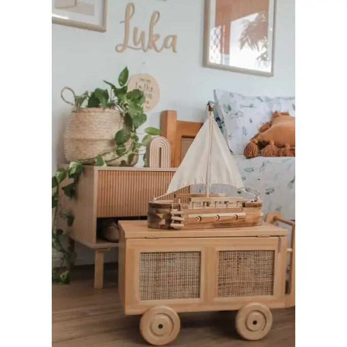 Wooden toy sailboat on wooden cart in child's bedroom