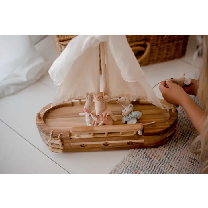 Child playing with wooden toy sailboat and mouse dolls