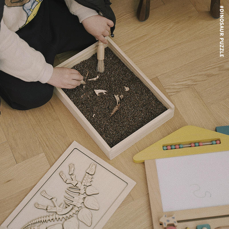 Child uncovering buried wooden pieces of stegosaurus puzzle kit