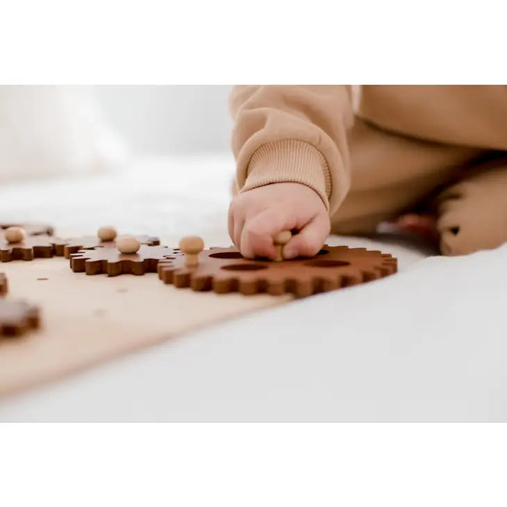 Child's hand playing with wooden gear construction play seet