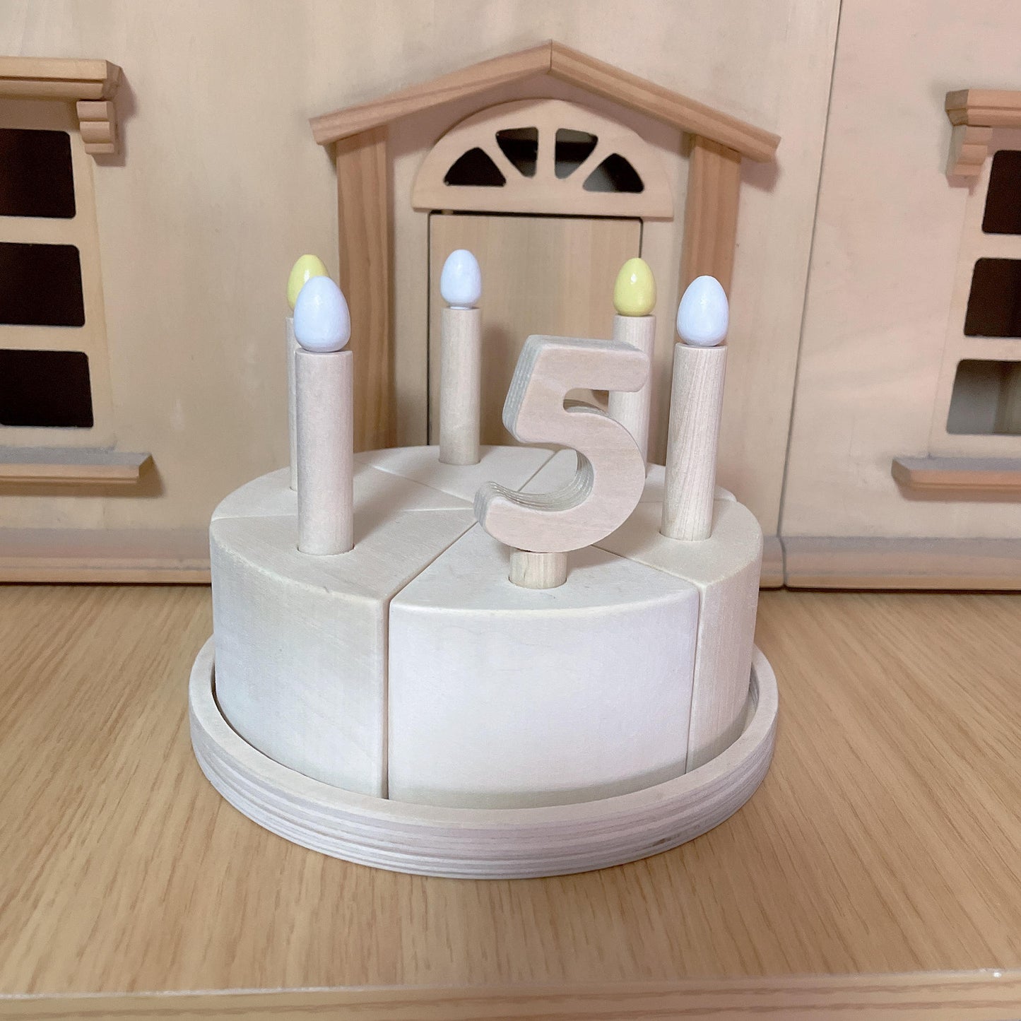 Wooden pretend cake set in front of wooden toy house