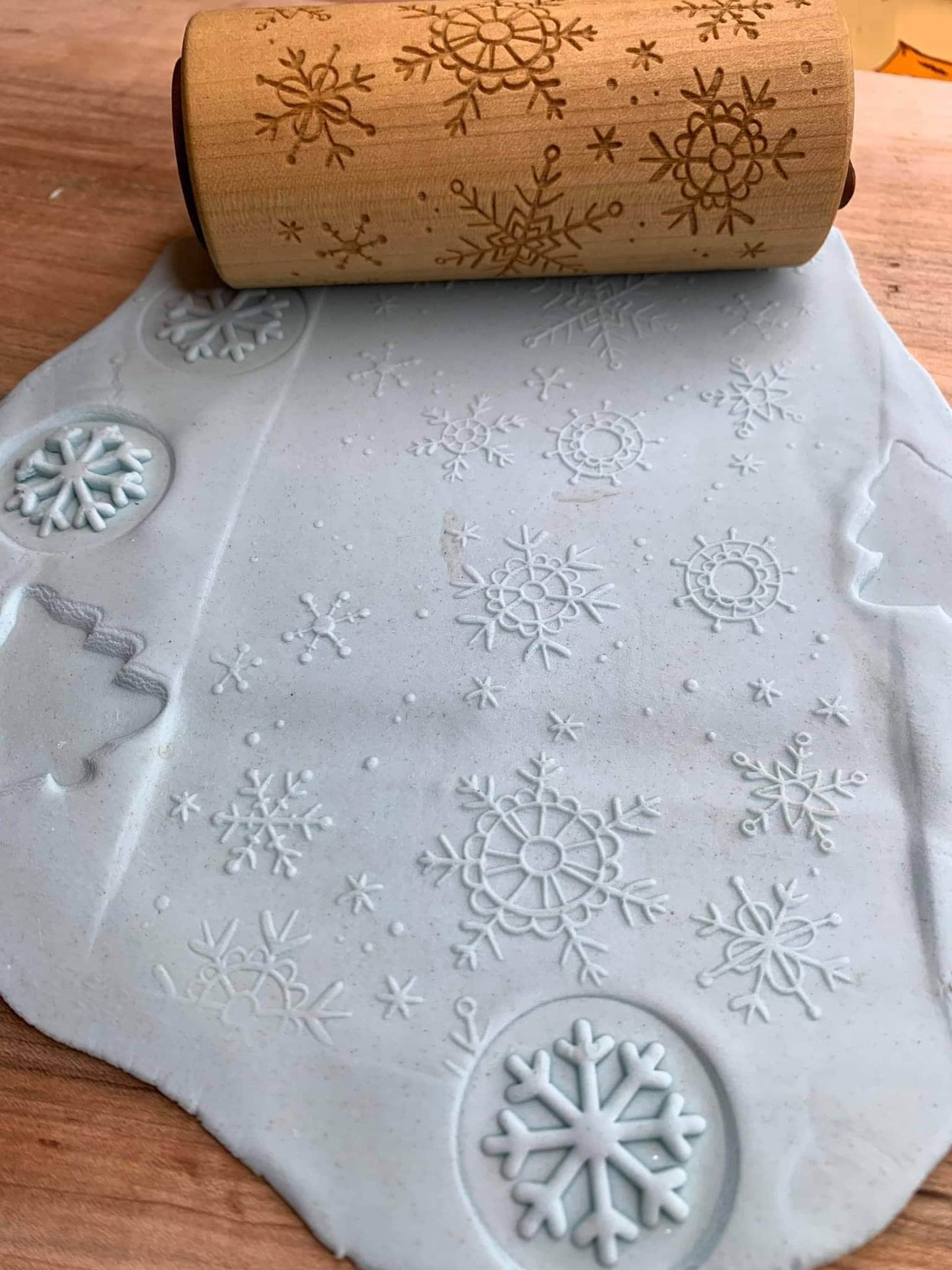 Play dough stamped with snowflake shapes next tp snowflake rolling pin